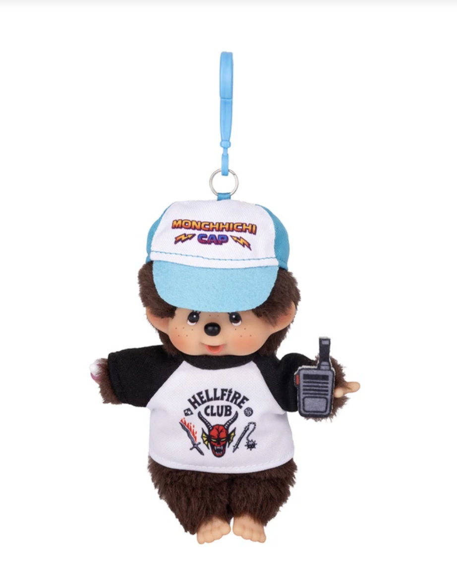 A plush monkey character keychain or bag charm with a blue wrist strap, wearing a white and blue cap with  text and a white and black shirt with 'HELLFIRE CLUB' graphics, holding a walkie-talkie against a plain white background.