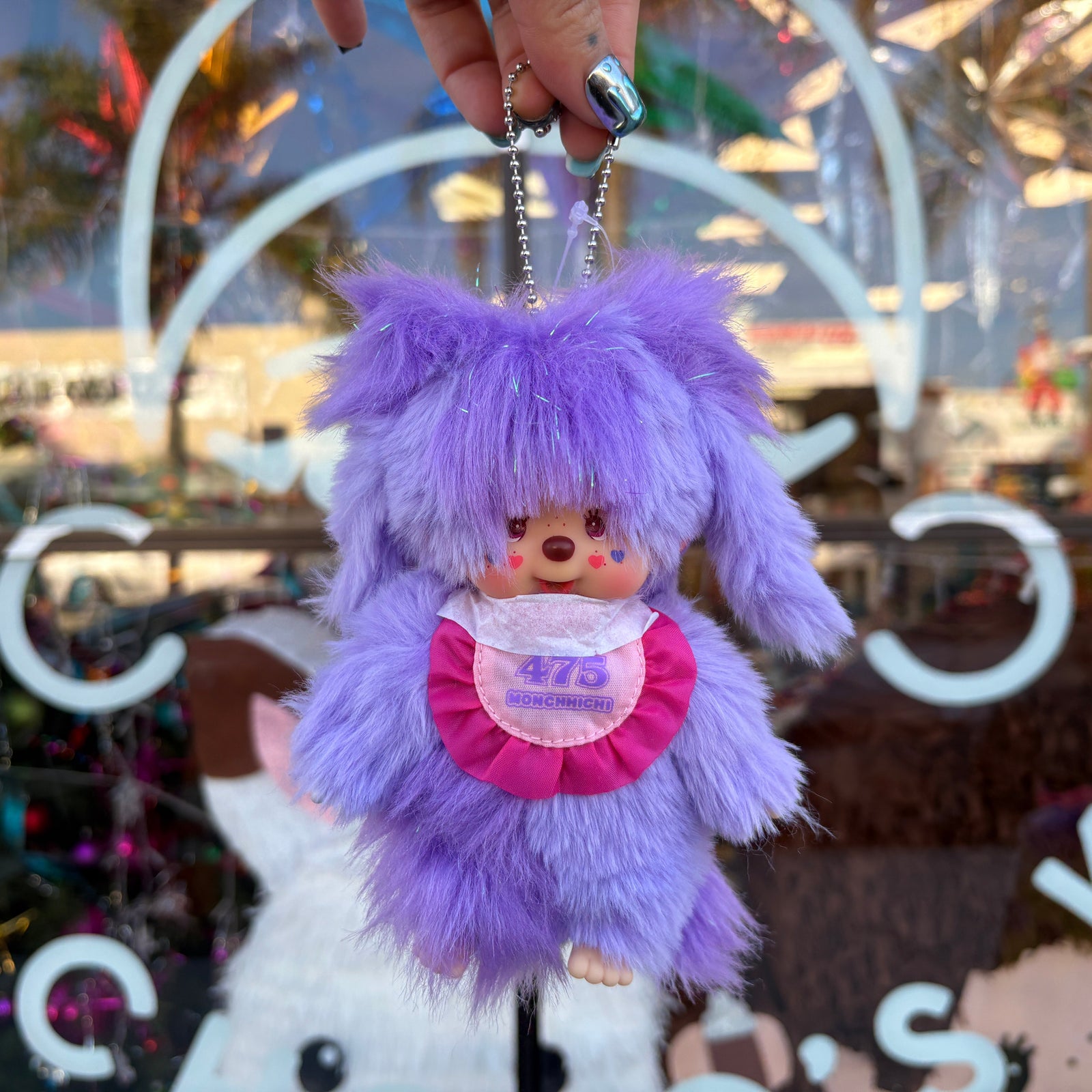 Purple fluffy keychain with Monchhichi character on a blurred background