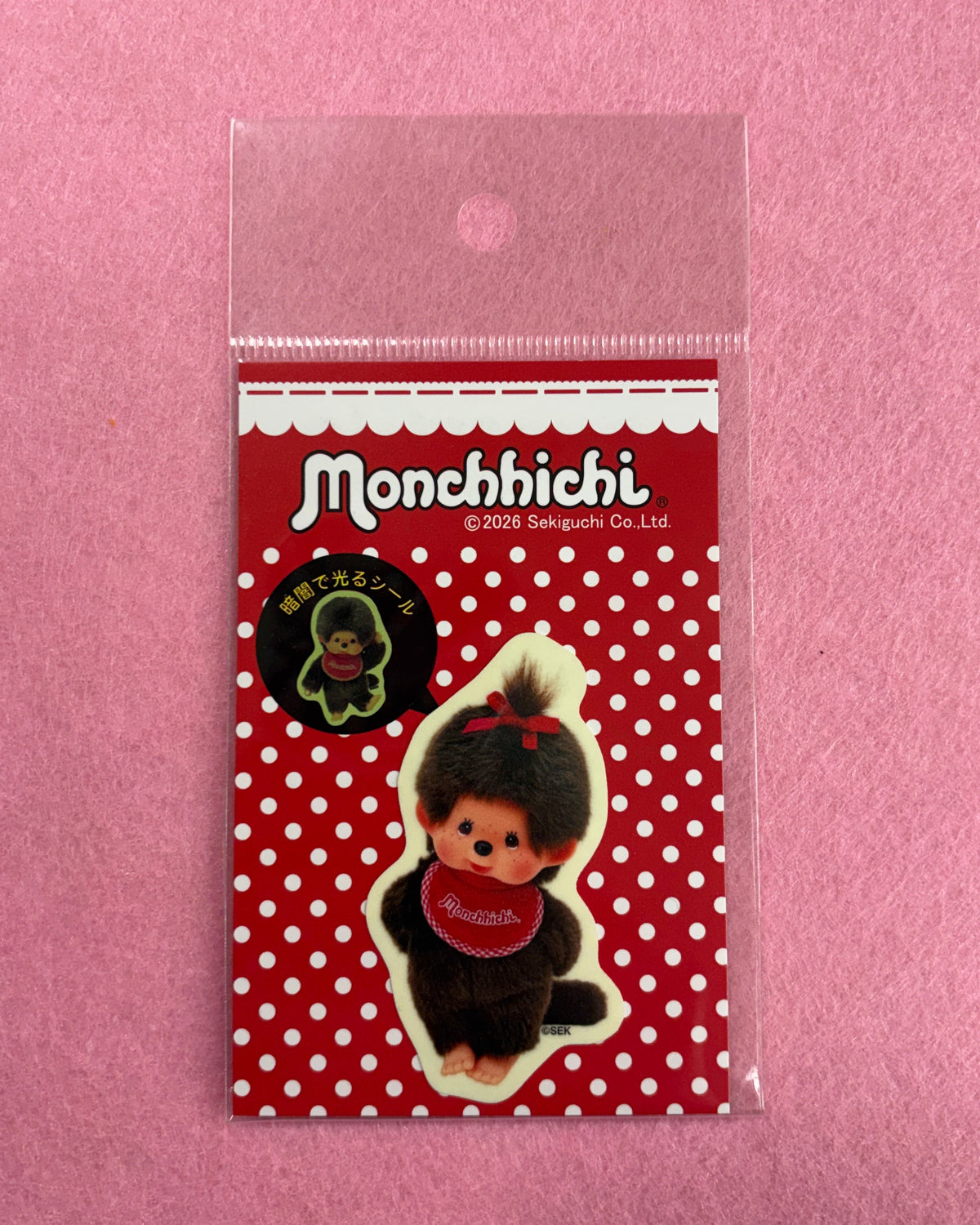 Small red polka dot notebook with a character design on a pink background