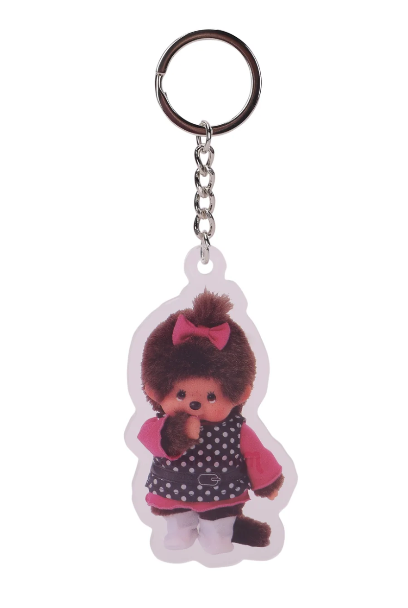 A plastic keychain featuring a stylized character with brown curly hair, a pink bow, and a pink-and-white polka-dot outfit, attached to a silver metal key ring and chain on a plain white background.